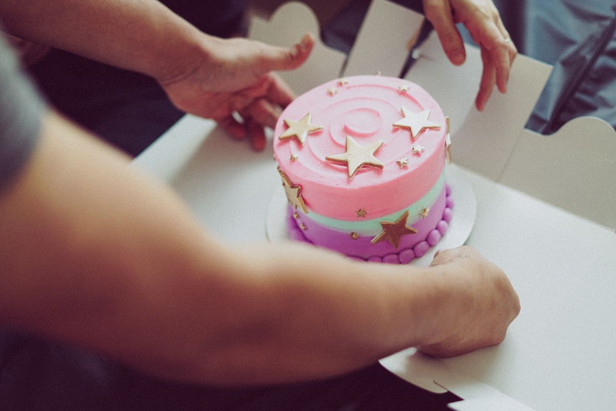 Close-up of a vibrant birthday cake with star decorations being placed in a box.