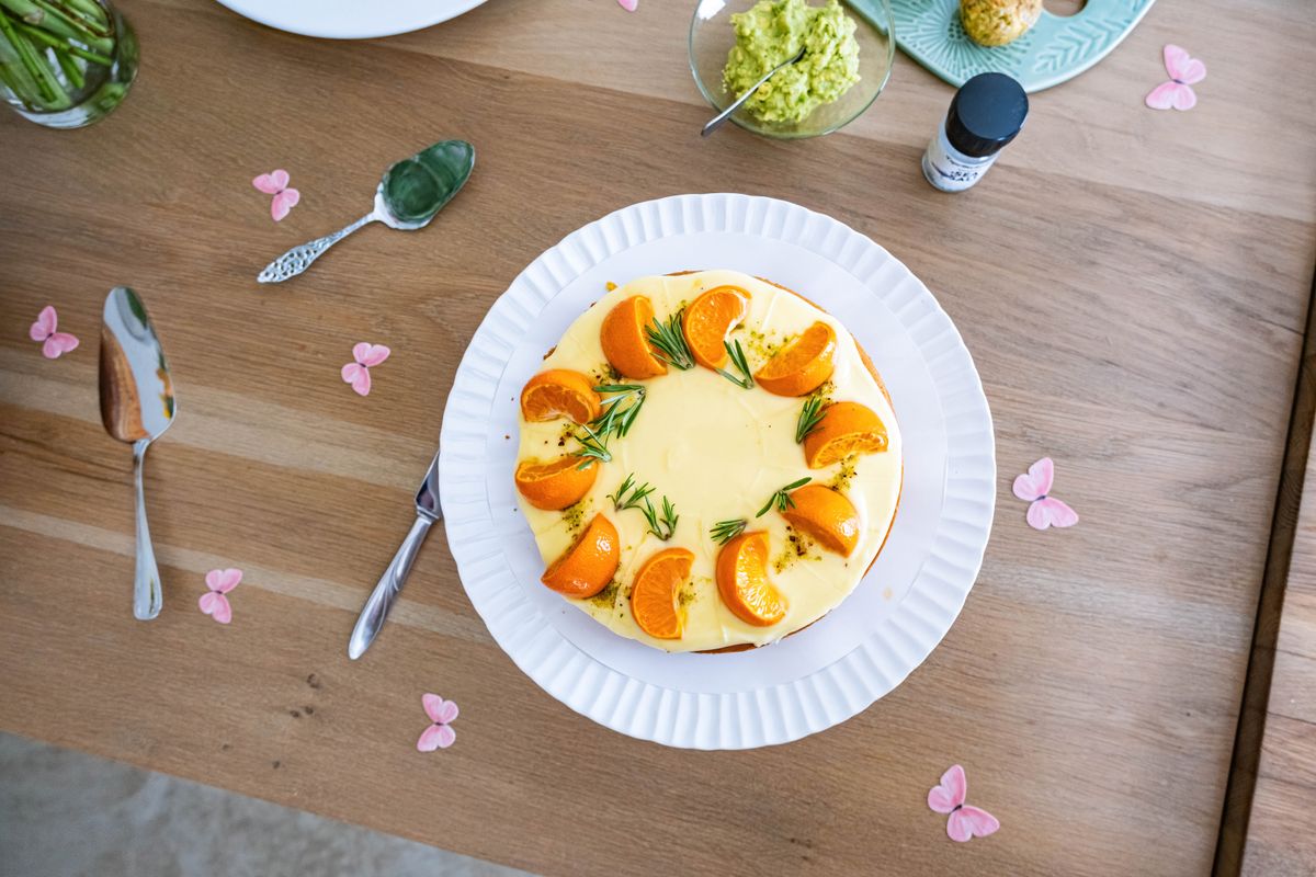 Top view of a beautifully garnished cheesecake with oranges and rosemary on a wooden table.